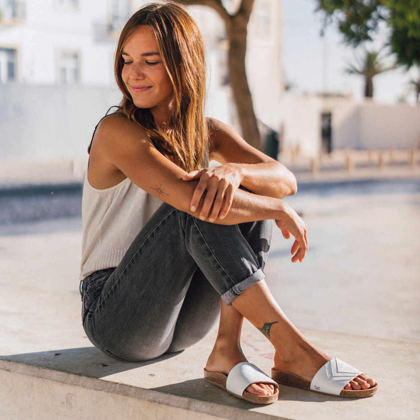 Weiße Sandalen vegan, Damen, Marke Fünve, Modell YANG, bequem, weibliches Modell auf Bank