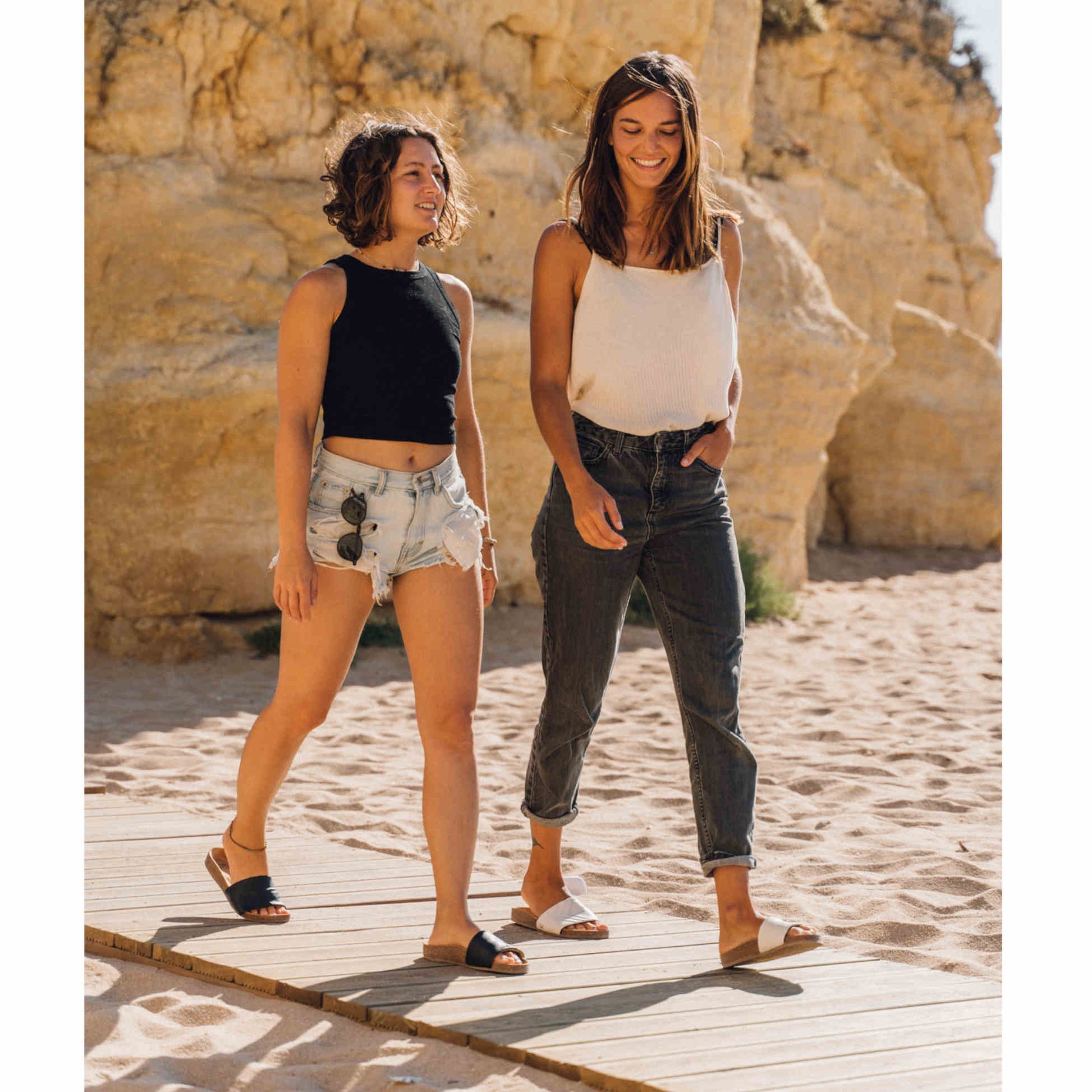 Vegane schwarze Sandalen, Marke Fünve, Modell: YIN, zwei Frauen am Strand, Marke Fünve