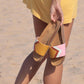 Gelbe Sandalen, vegan mit Fußbett, Farben Senf, Terracotta, Weiß, Rosa; Marke Fünve, Modell Dawn, in der Hand am Strand